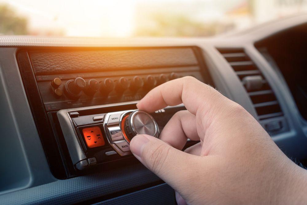 A Person Adjusts the Volume Knob on a Car Stereo — Norm Beatty's Auto Electrical Service In Long Jetty, NSW