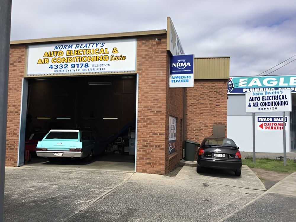 Two Cars Are Parked in Front of a Building — Norm Beatty's Auto Electrical Service In Long Jetty, NSW
