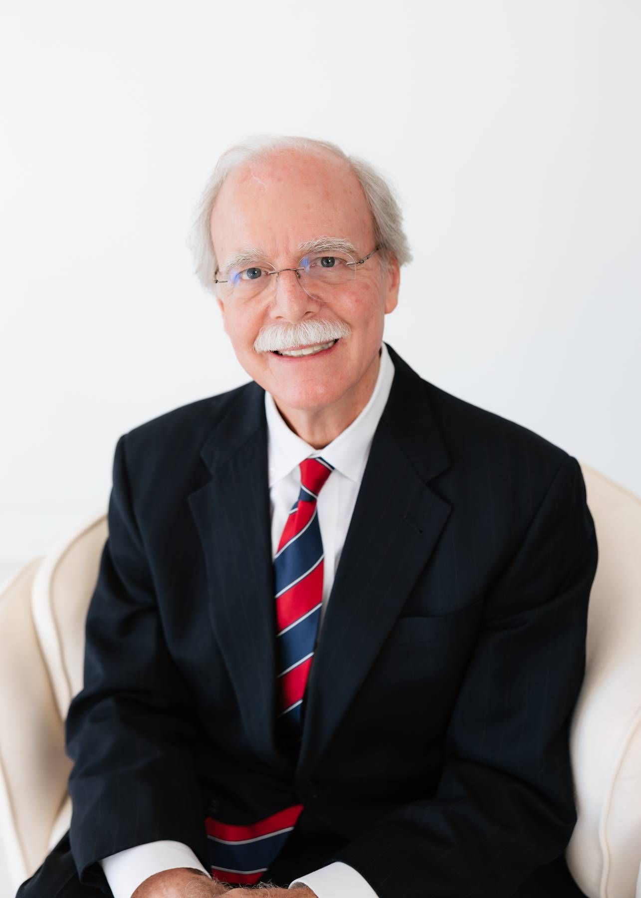 Professional headshot of Robert Floyd Davis in a navy blazer and light blue shirt, seated against a white background