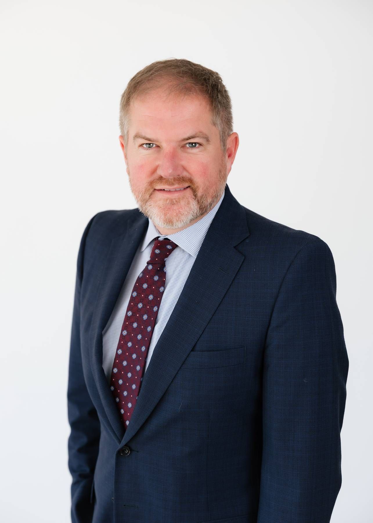 Professional headshot of Robert Floyd Davis in a navy blazer and light blue shirt, seated against a white background