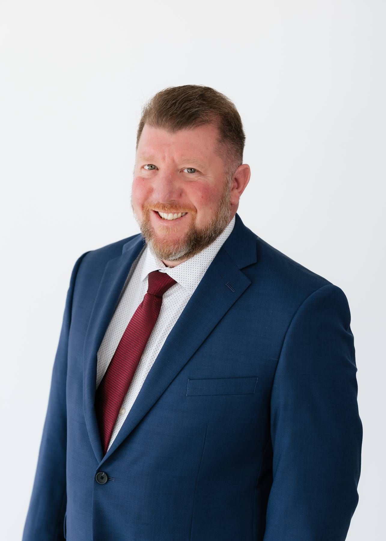 Professional headshot of Robert Floyd Davis in a navy blazer and light blue shirt, seated against a white background