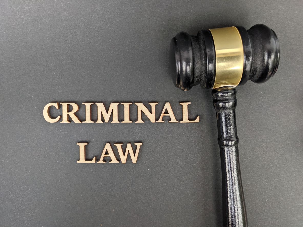 Criminal law text beside a judge’s gavel on a dark background