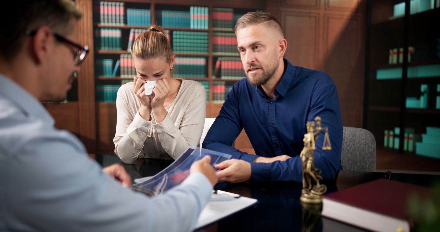 Three people in a meeting, with one person speaking across a table in a modern office.