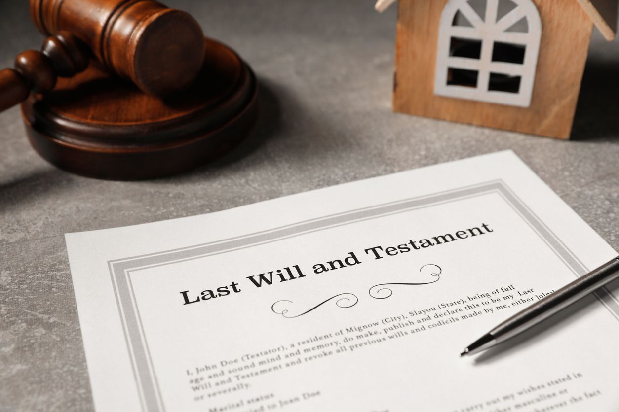 Last will and testament document with gavel, pen, and house model on a desk