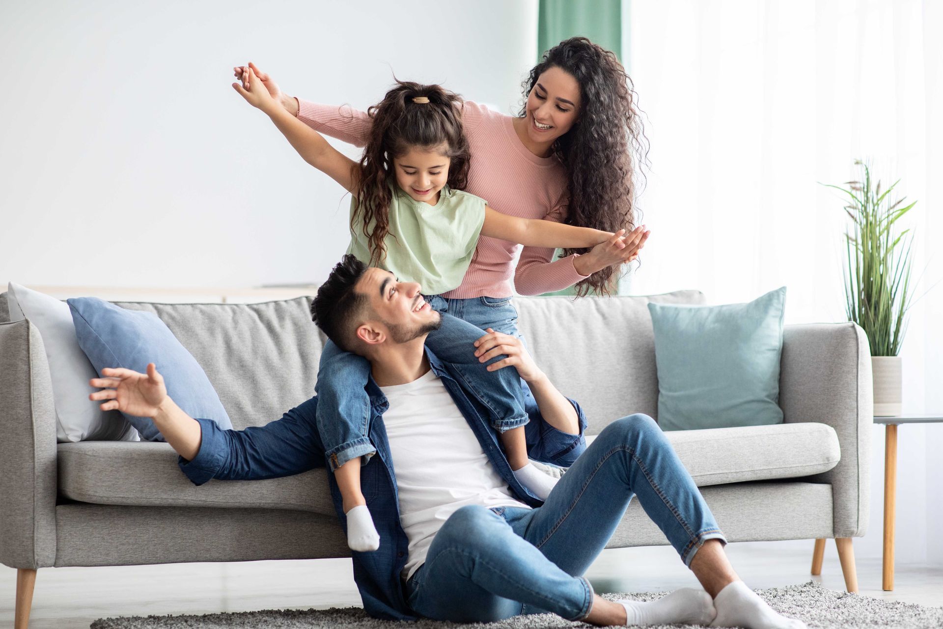 A man is sitting on the floor with a little girl on his shoulders