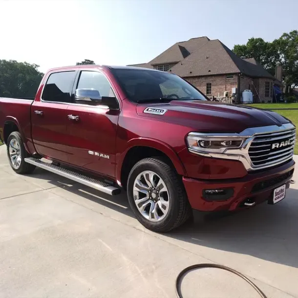 Red RAM pickup truck parked in a driveway beside a house on a sunny day