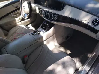 Luxury car interior with beige leather seats, chrome dashboard controls, and sunlight on the front passenger area