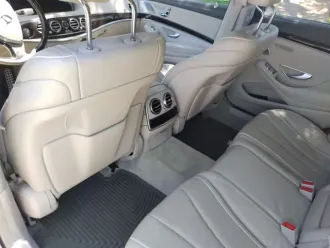 Beige leather car interior with rear seats, center vents, and front console visible.