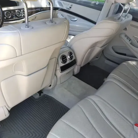 Beige leather car interior with rear seats, center console vents, and dark floor mats