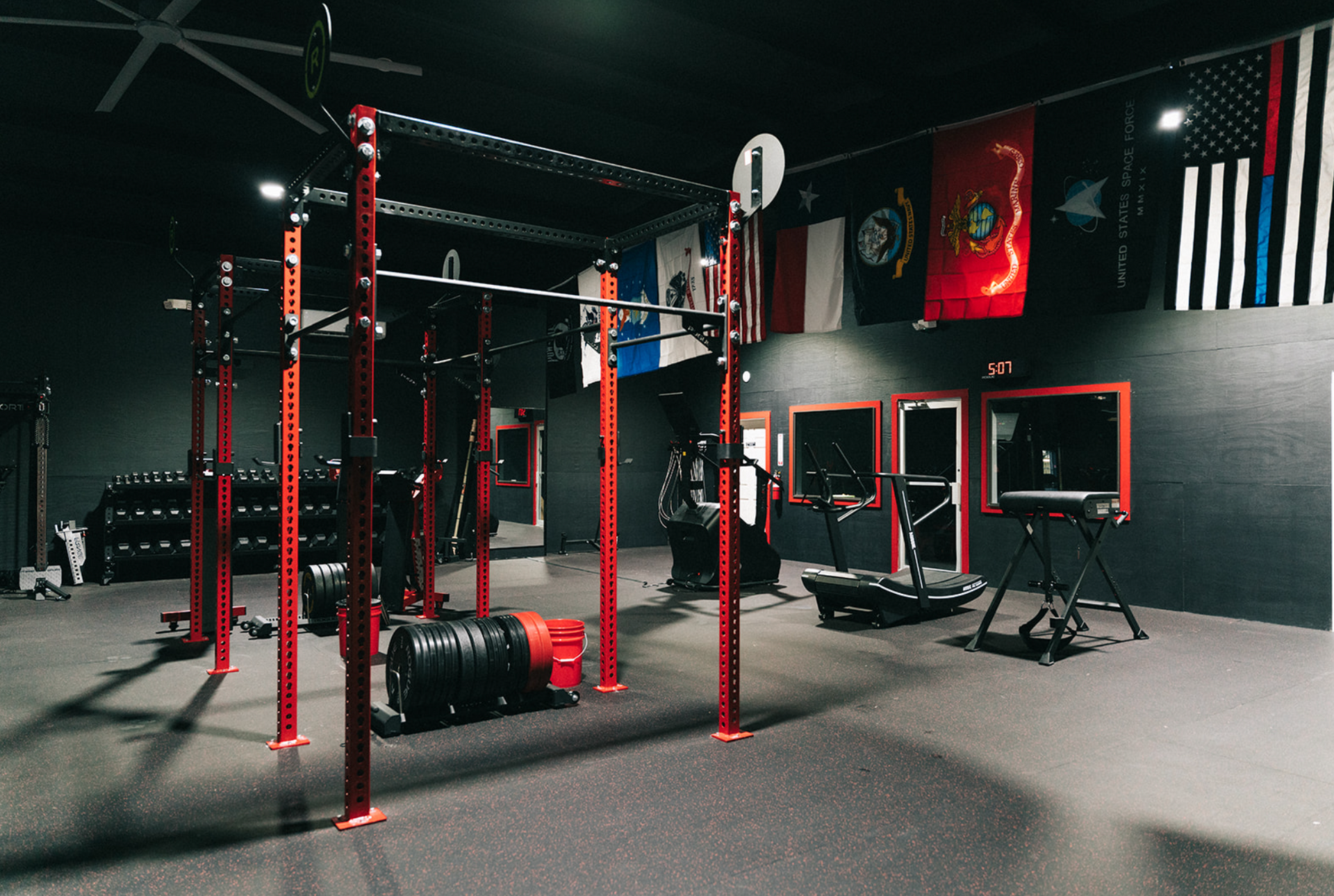 Red weightlifting equipment in a gym with flags and a dark interior.