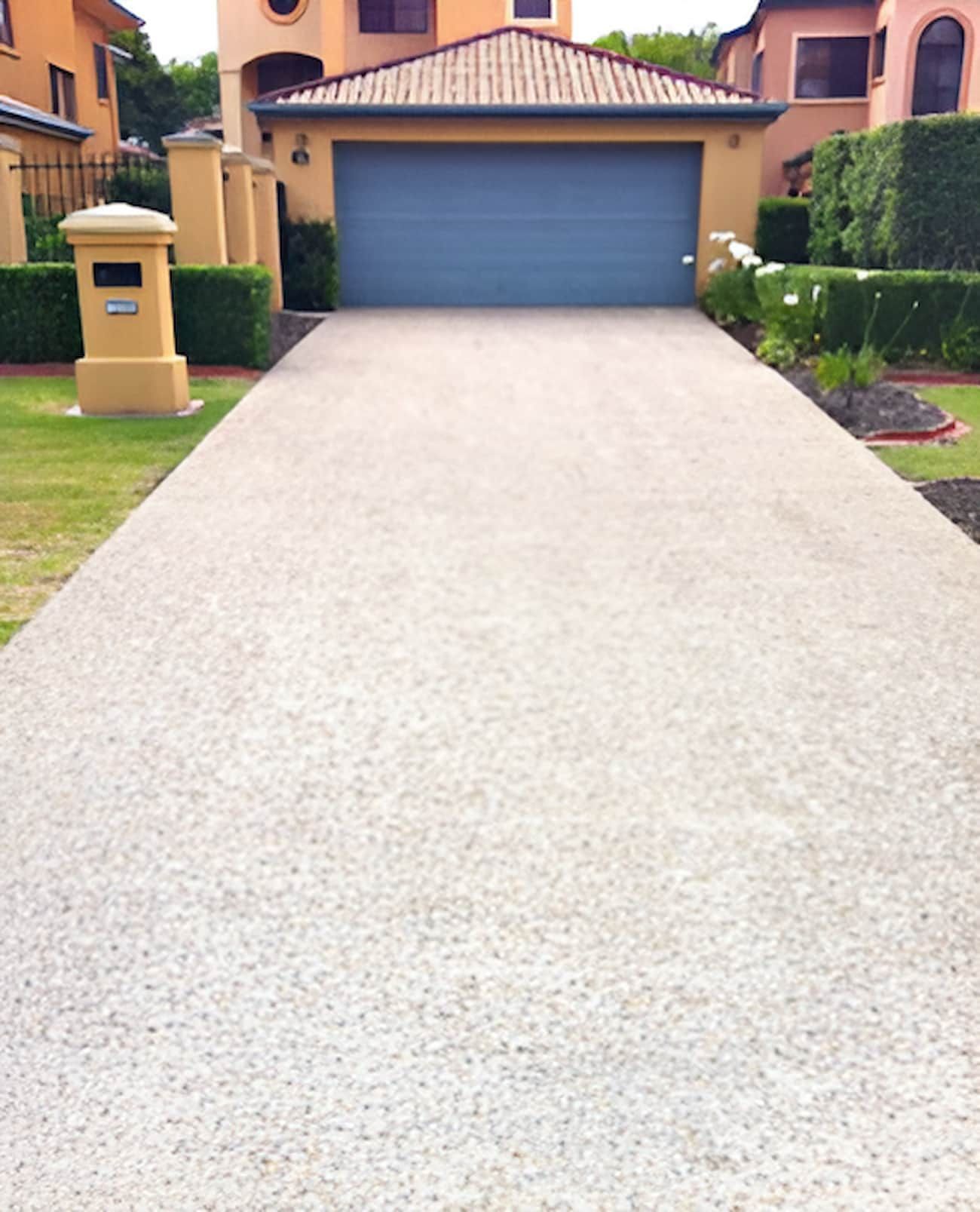 A Driveway Leading To A House With A Blue Garage Door — EcoPro Pressure Cleaning In Broadbeach Waters, QLD