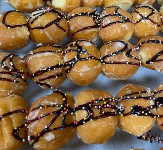 Mini donuts drizzled with chocolate and colorful sprinkles on a tray