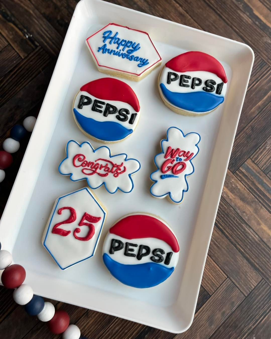 White tray of red, white, and blue Pepsi-themed decorated cookies on a wooden table