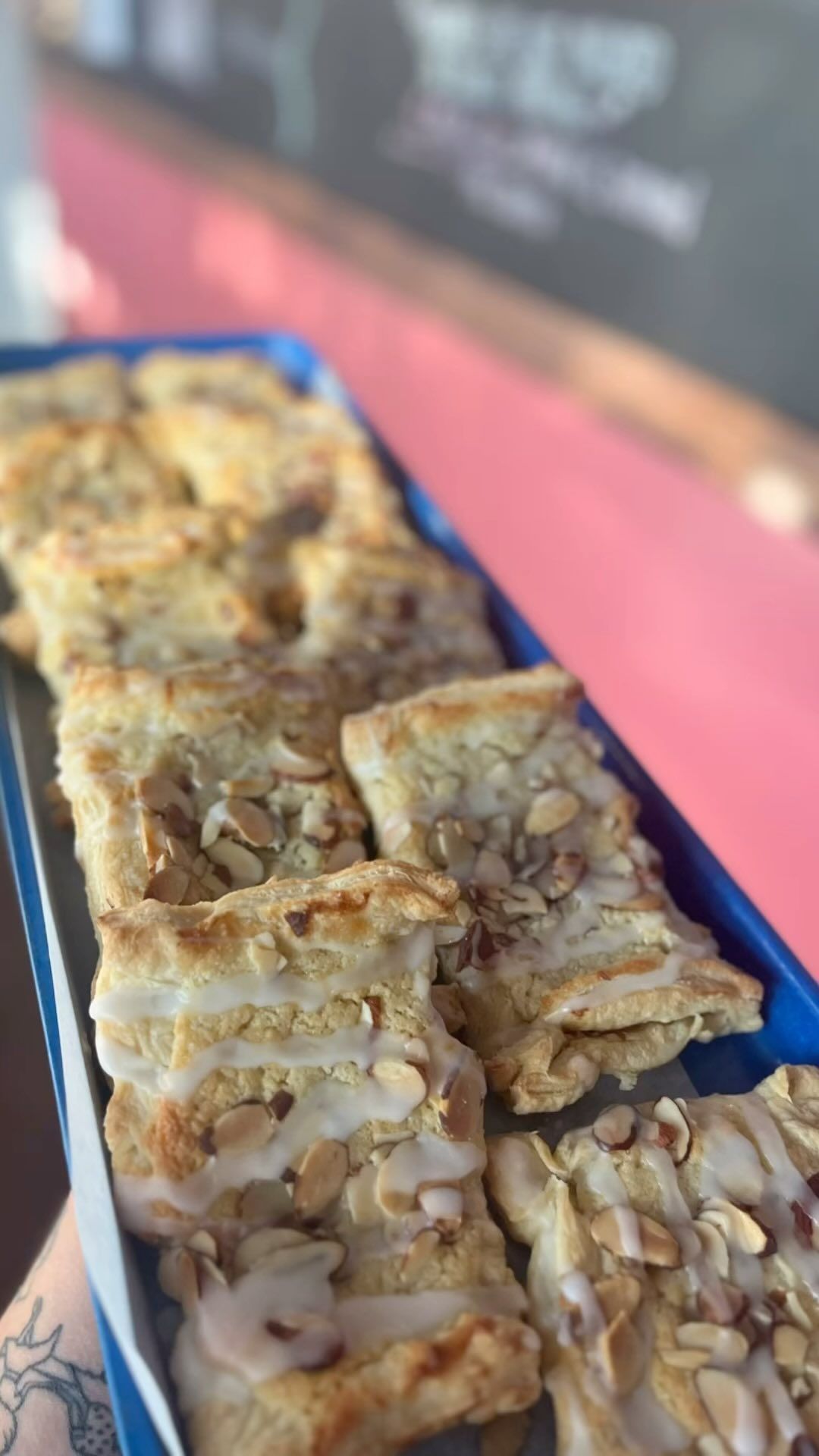 Tray of glazed pastries topped with chopped nuts, arranged on a black platter