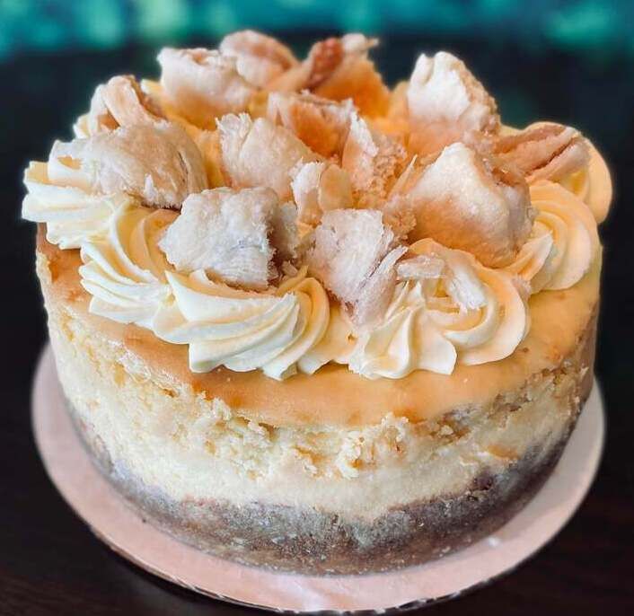 Round layered cake with cream swirls and coconut flakes on top, shown on a white cake board.