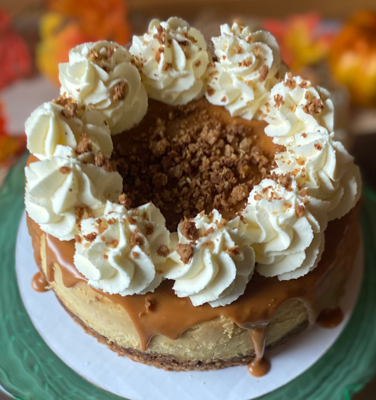 Caramel-drizzled cheesecake topped with whipped cream swirls and crumb center on a plate