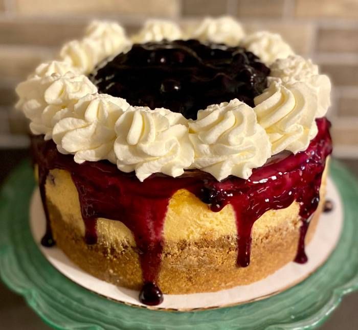 Chocolate cake with cream frosting and dark berry glaze dripping over the sides