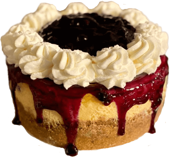 Cheesecake topped with whipped cream and dark berry sauce dripping over the sides