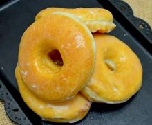 Glazed golden donuts stacked on a black tray