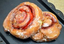 Glazed cinnamon roll pastries on a dark tray