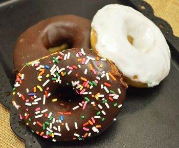 Three donuts with chocolate, white, and sprinkled chocolate icing on a tray