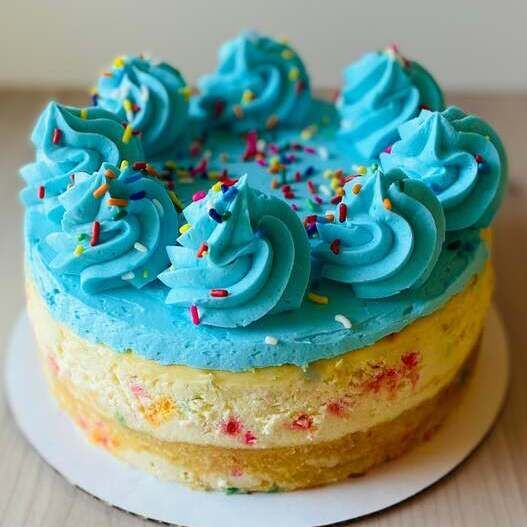 Blue frosted cake with colorful sprinkles on a white board
