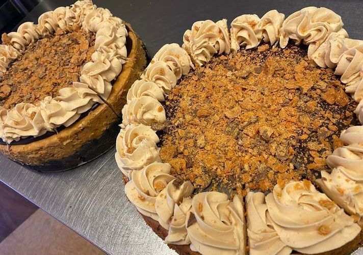 Two large decorated cakes with crumb topping and cream swirls on a table