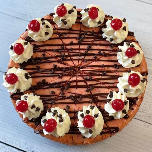 Chocolate-drizzled cake topped with whipped cream, cherries, and chocolate chips on a plate