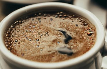 Close-up of a white mug filled with frothy coffee and foam bubbles
