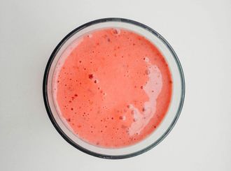 Top-down view of a glass bowl filled with pink smoothie or soup, with small bubbles on top