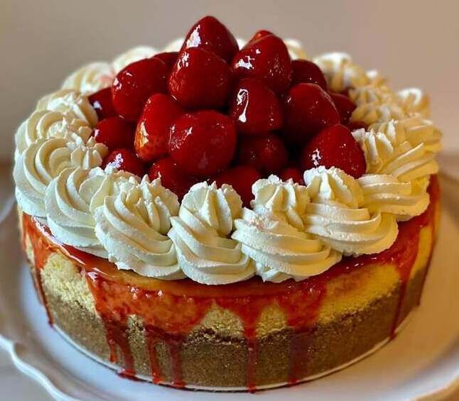 Strawberry-topped layer cake with whipped cream frosting and strawberry glaze on a white plate