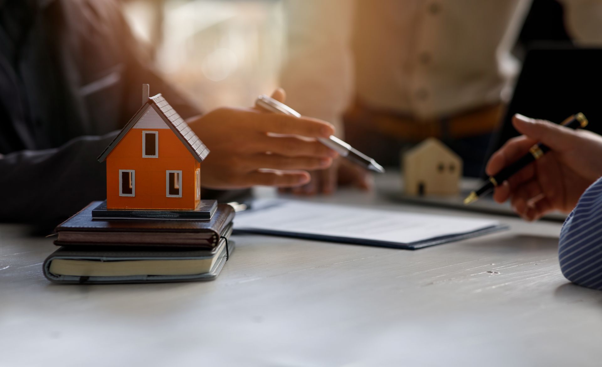 Hands reviewing real estate models and documents on a desk