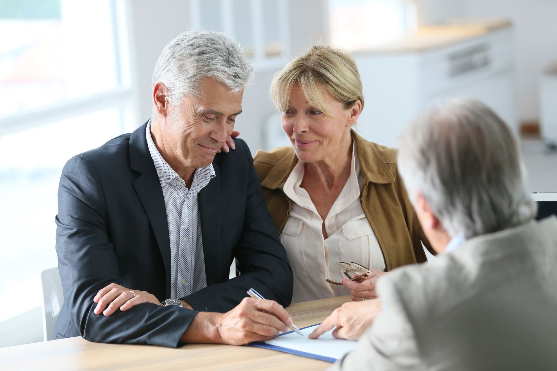 Two people in a meeting reviewing documents across a desk in a bright office