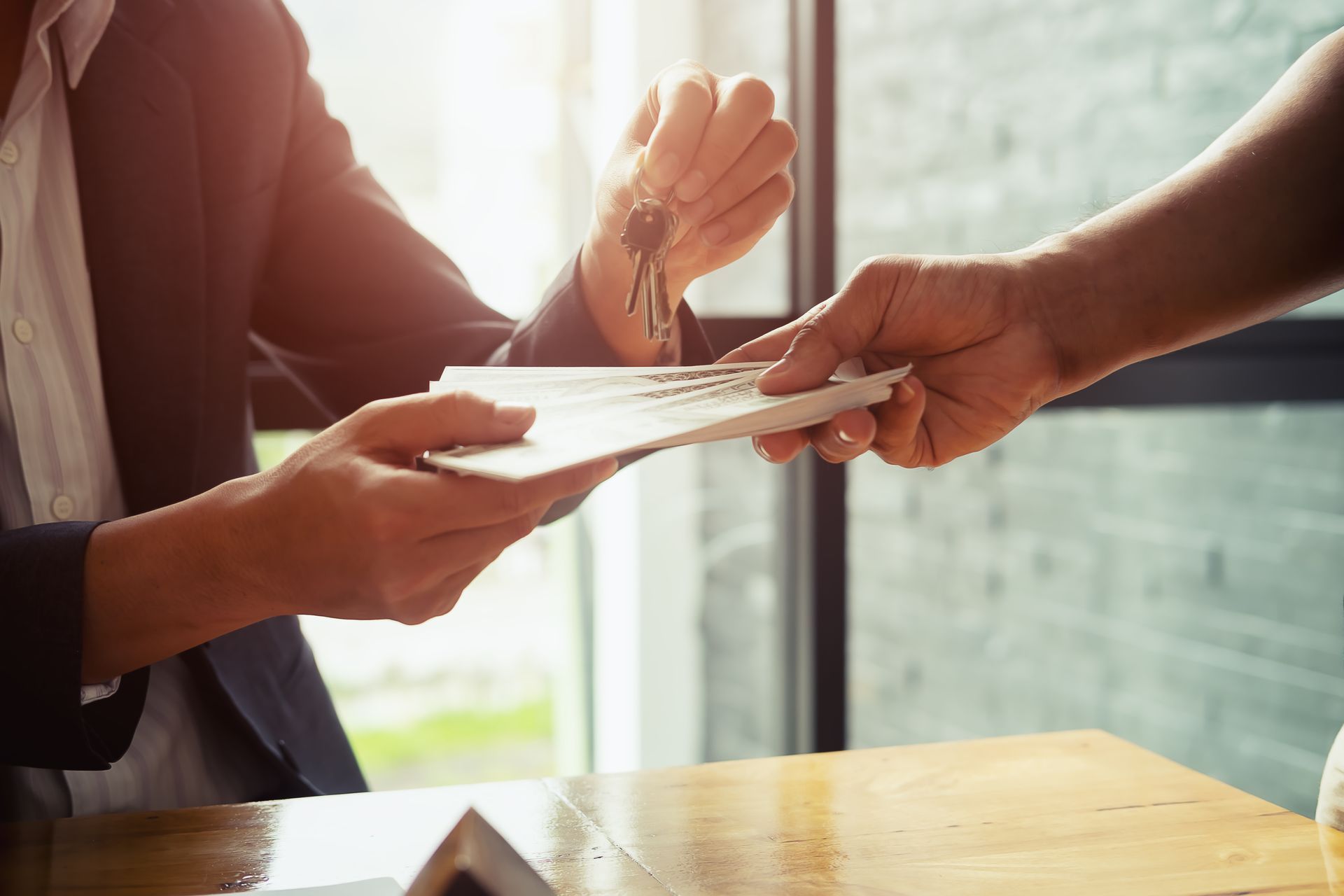 Hands exchanging a document over a wooden table in a bright office