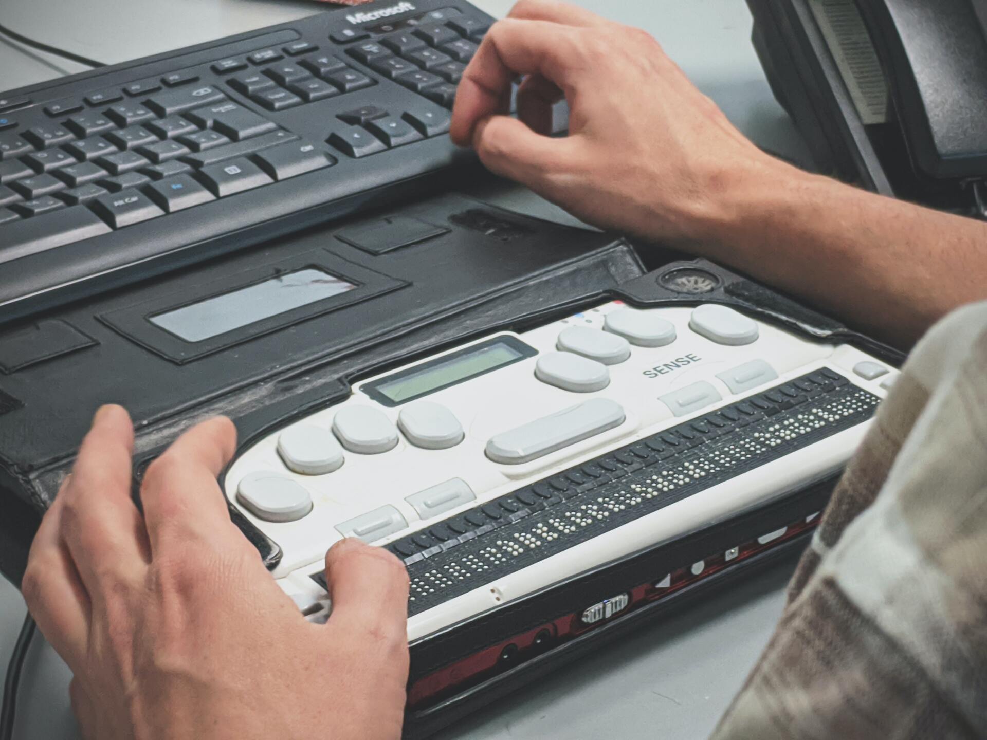 man's hands using an assistive technology connected to a computer keyboard