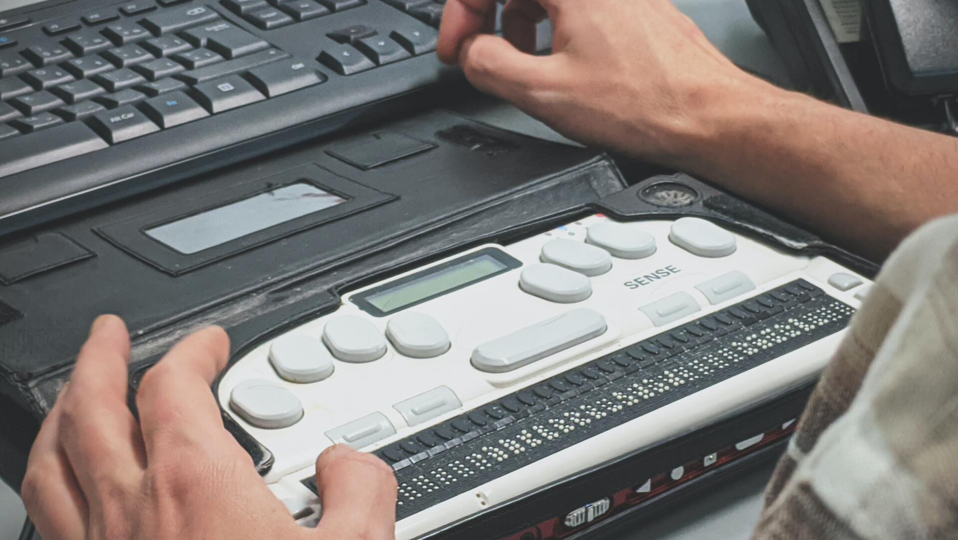 a pair of man's hands using an accessibility keyboard