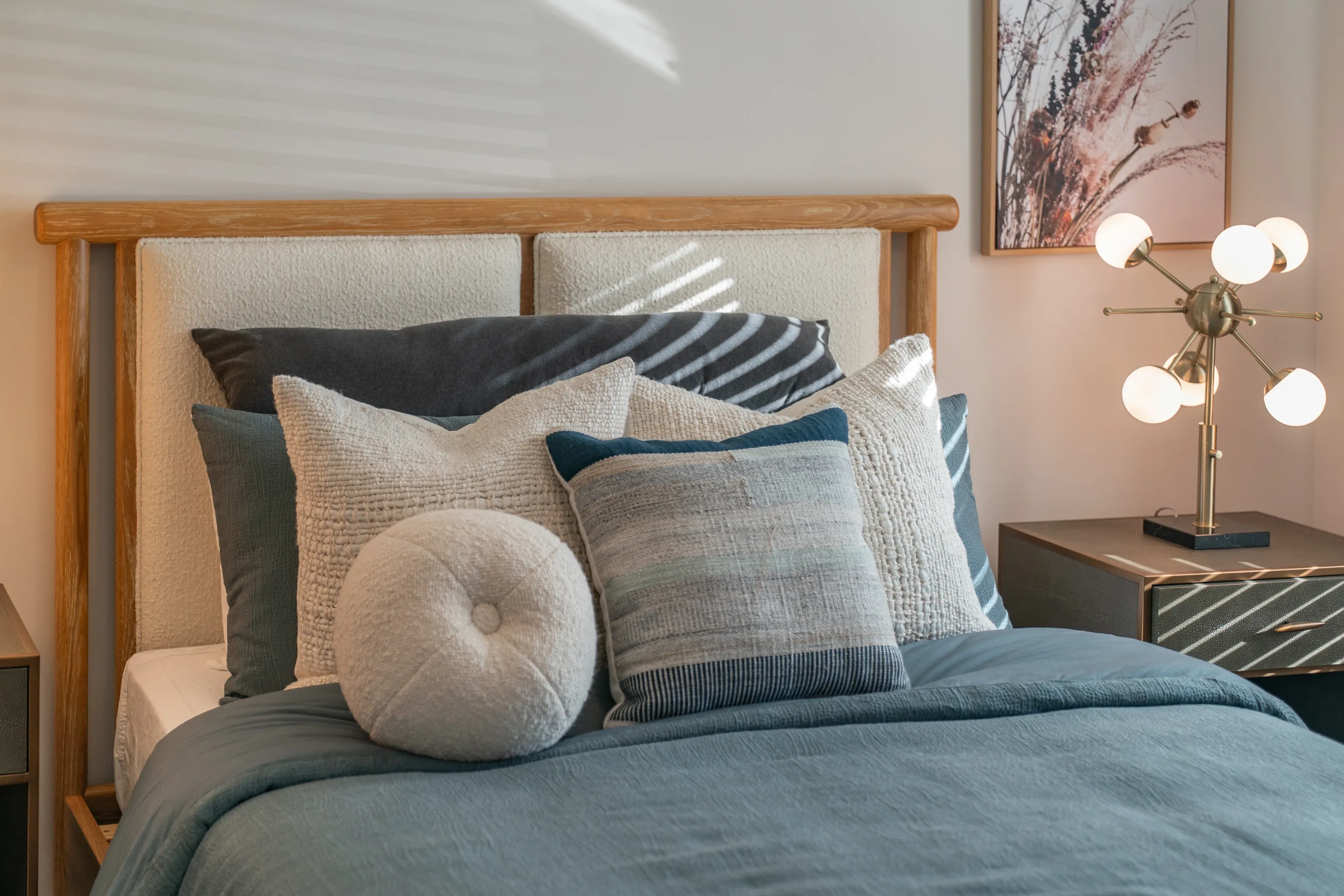 Cozy bedroom with a plush bed, an assortment of decorative pillows, and a modern bedside lamp.