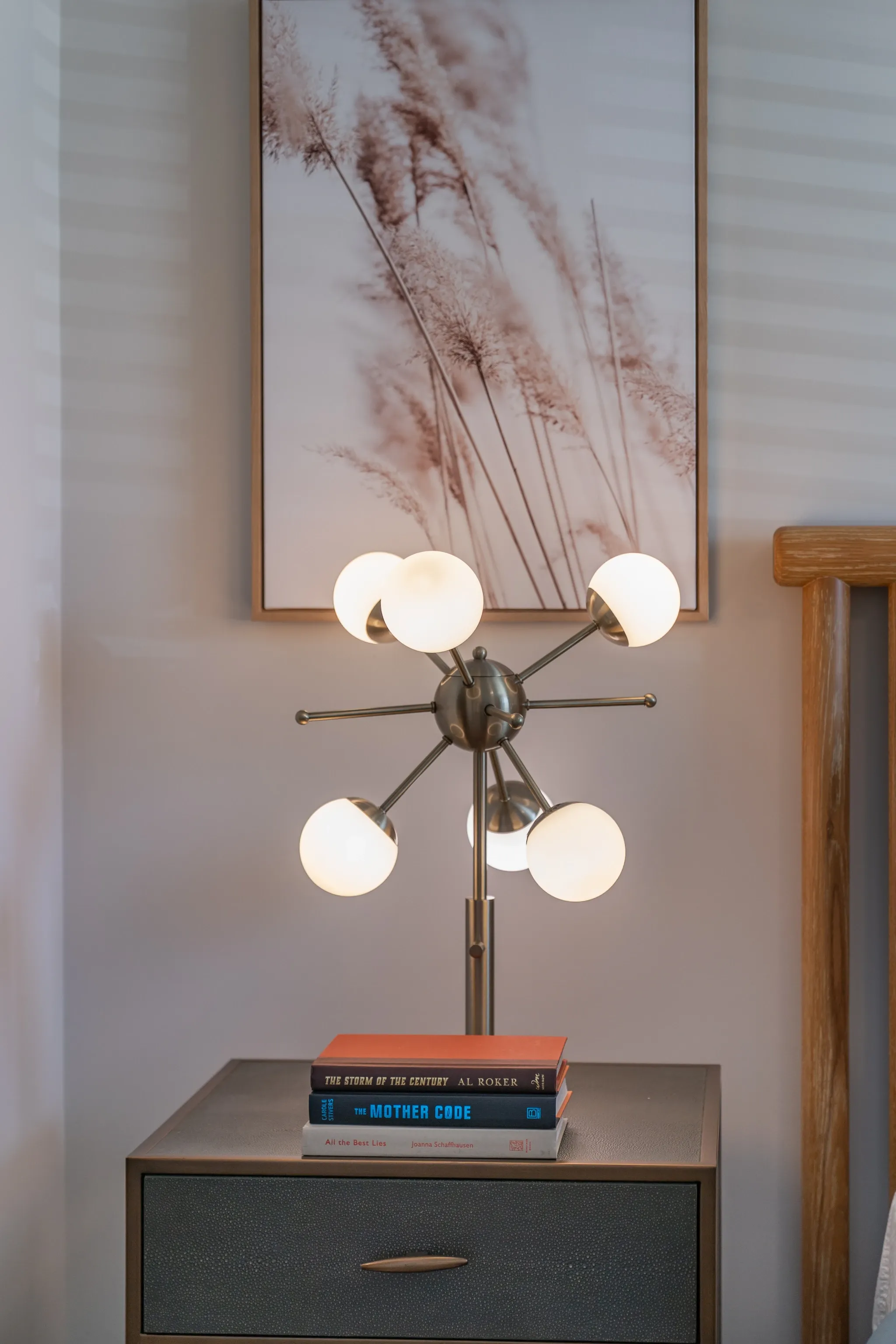 Bedside table with stacked books and an art deco lamp in a bedroom.