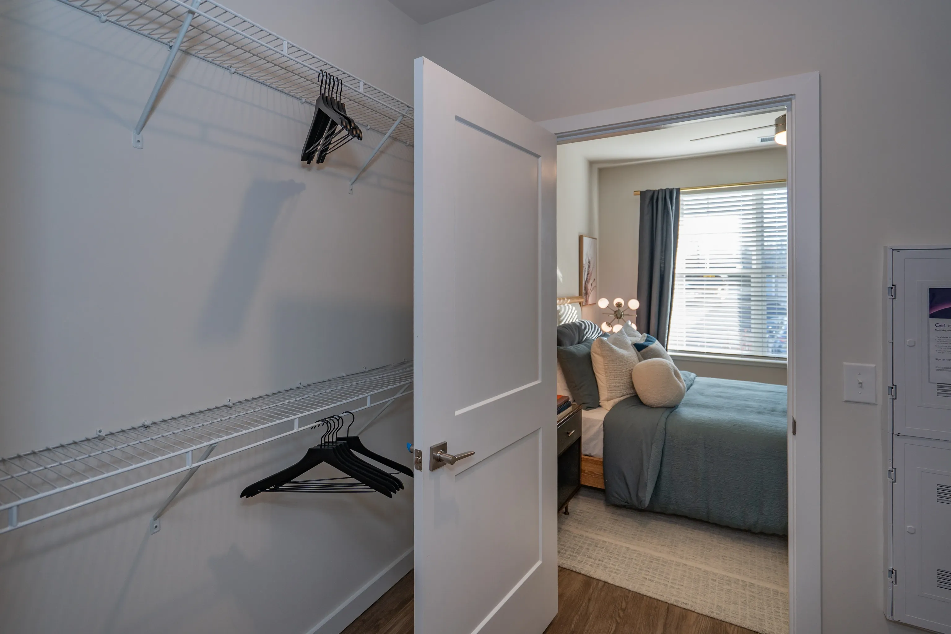 Empty closet with wire shelving and hangers next to a bedroom.