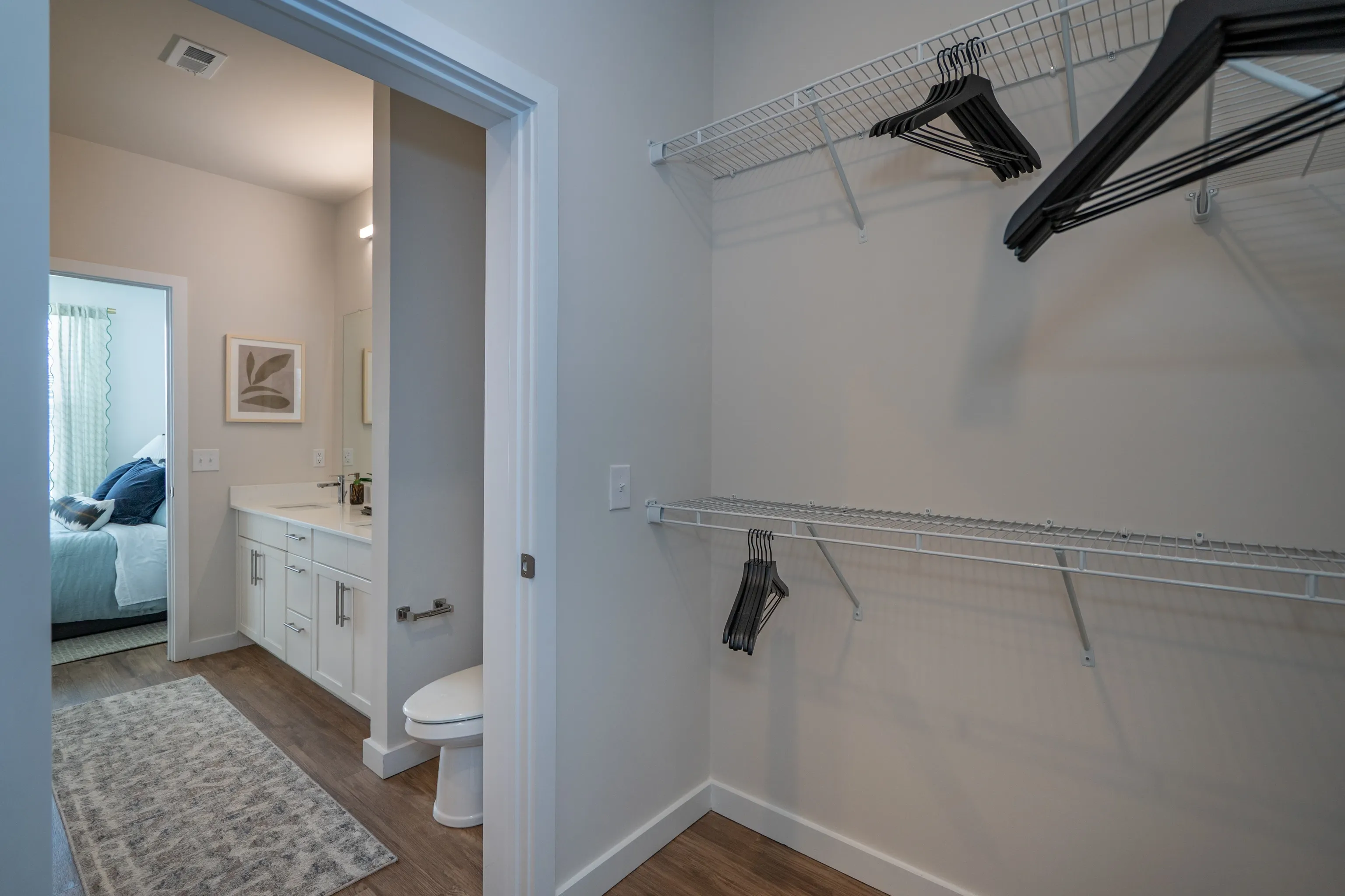 Closet with wire shelving and hangers, view into bathroom and bedroom.