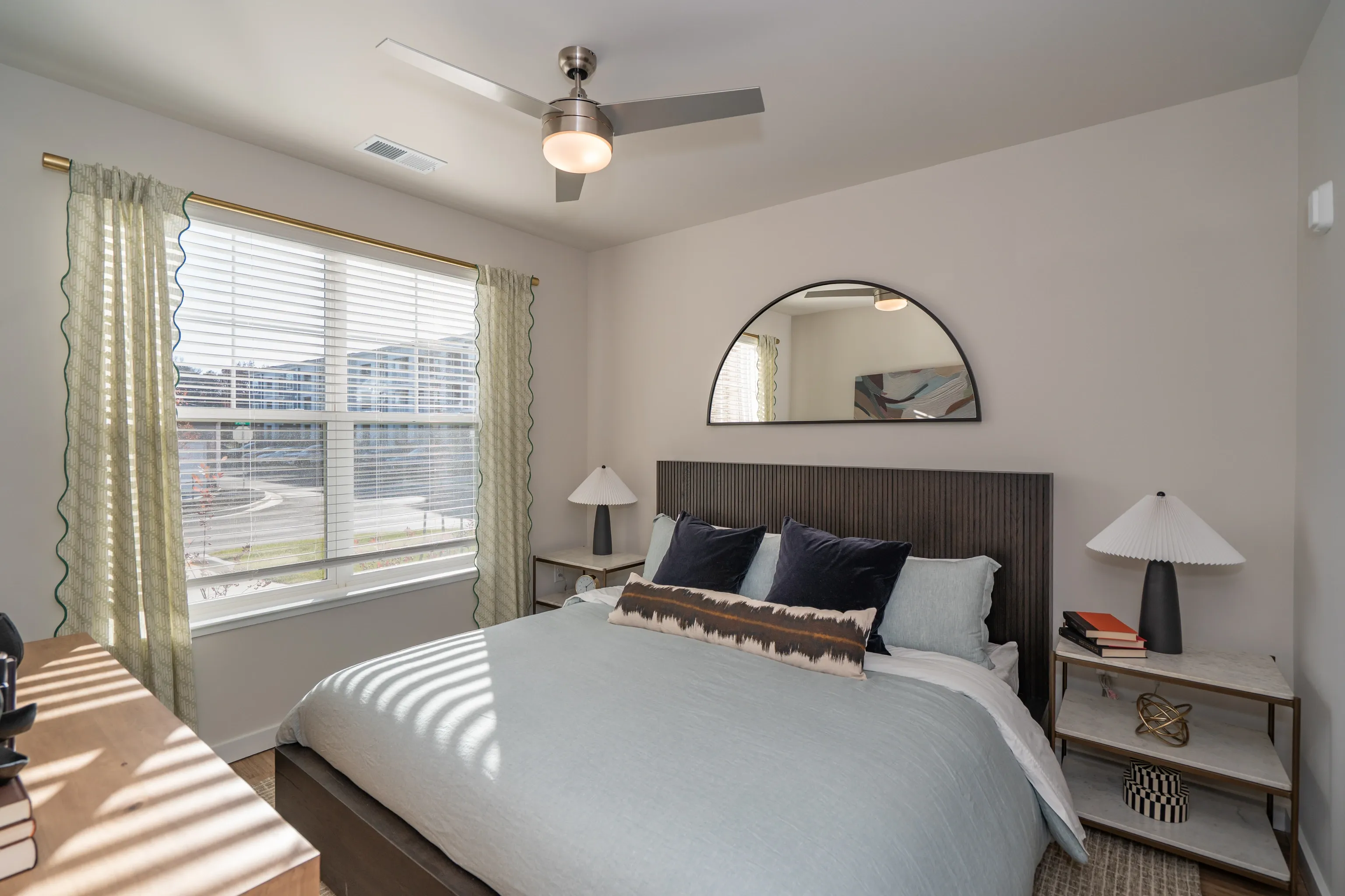 Cozy bedroom with a large bed, dresser, nightstands, and a ceiling fan.
