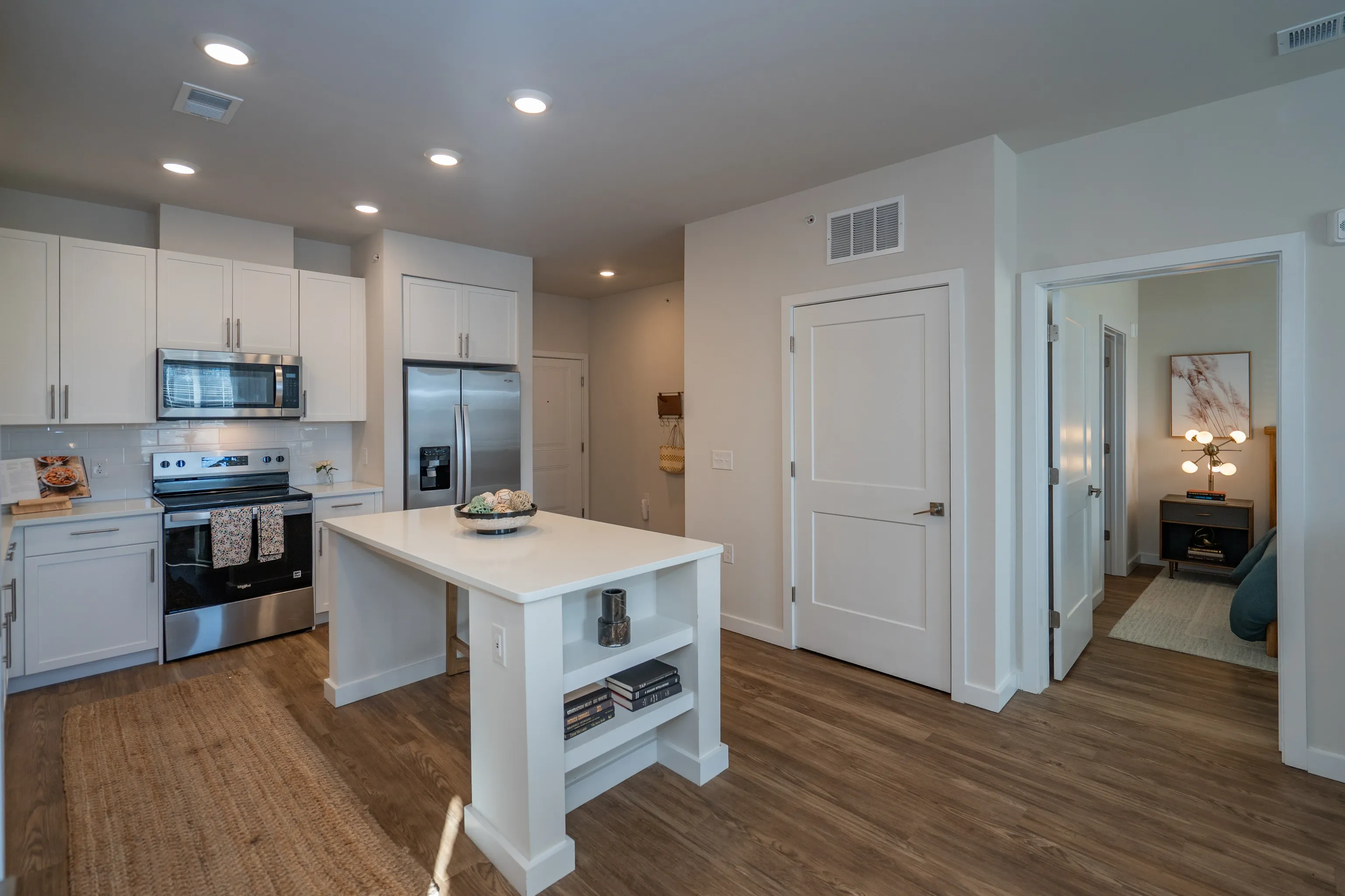 Modern kitchen and living area with white cabinets, stainless steel appliances, and an island.