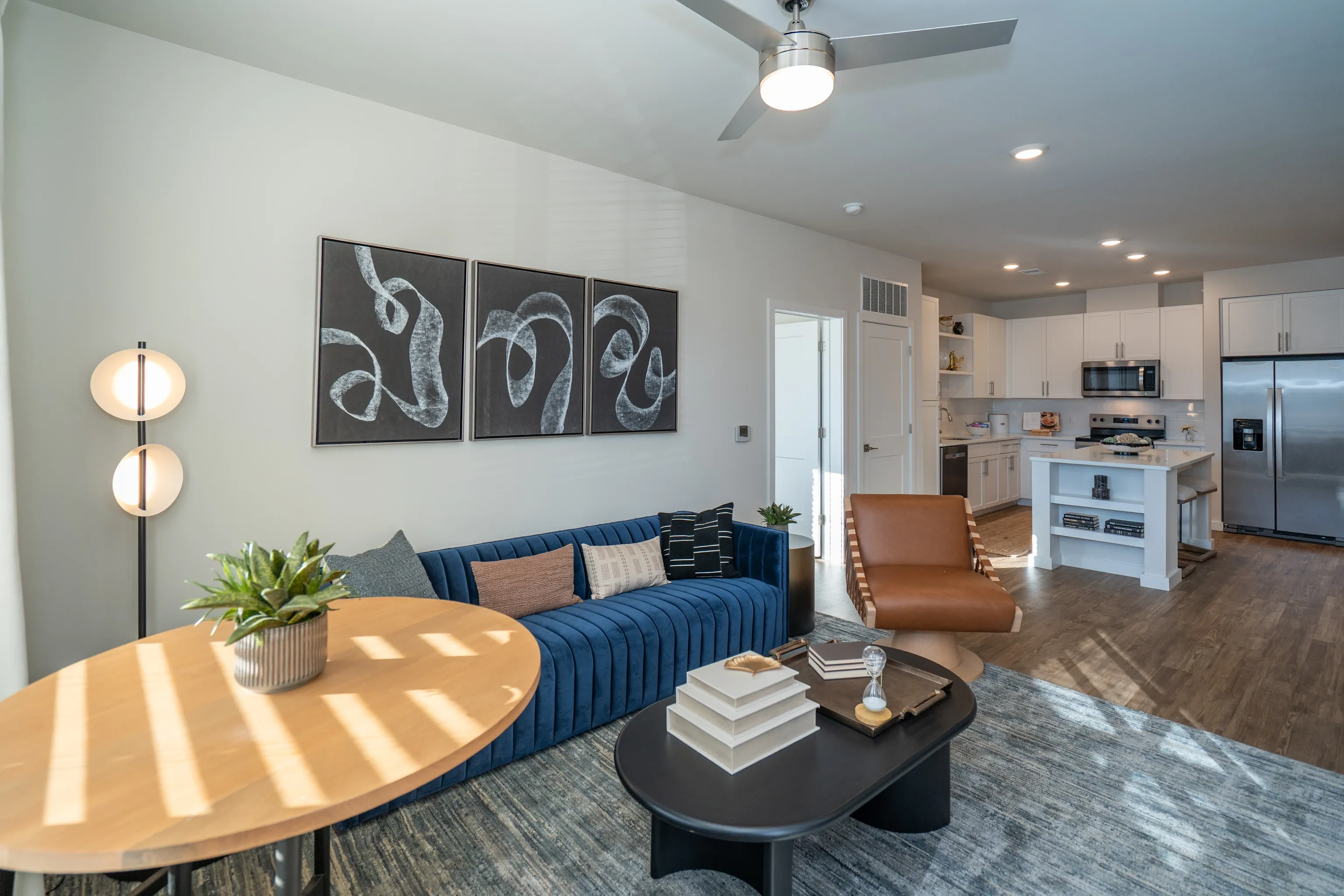 Modern living room and kitchen area with blue sofa, coffee table, and island.
