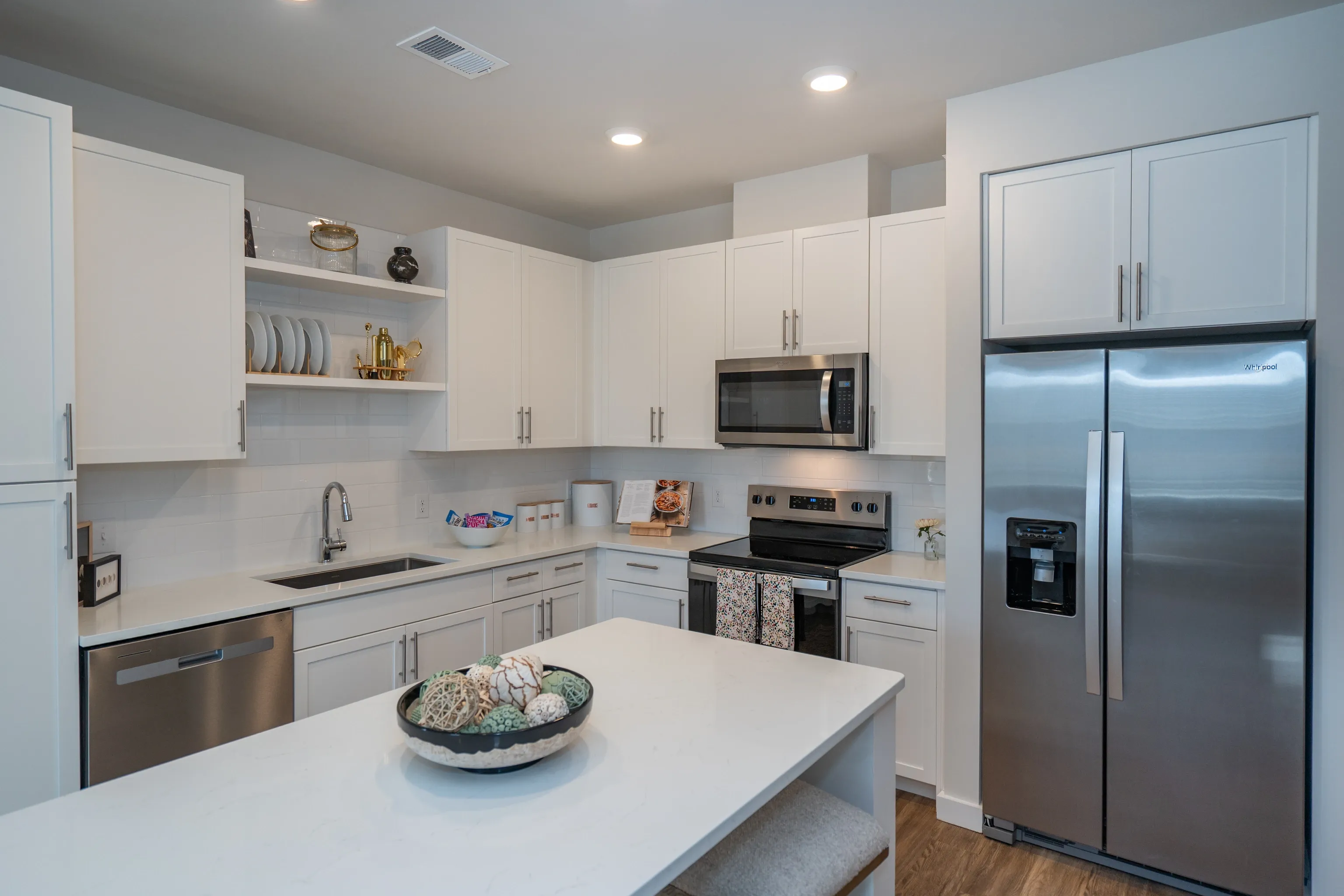 Modern kitchen with white cabinets, stainless steel appliances, and a large island.