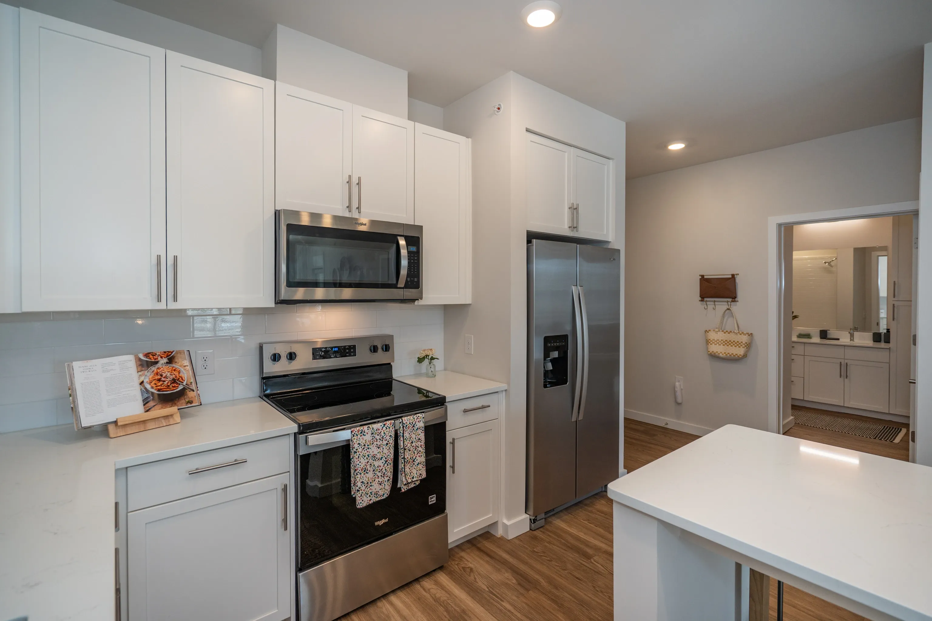 Modern kitchen with stainless steel appliances, white cabinets, and quartz countertops.