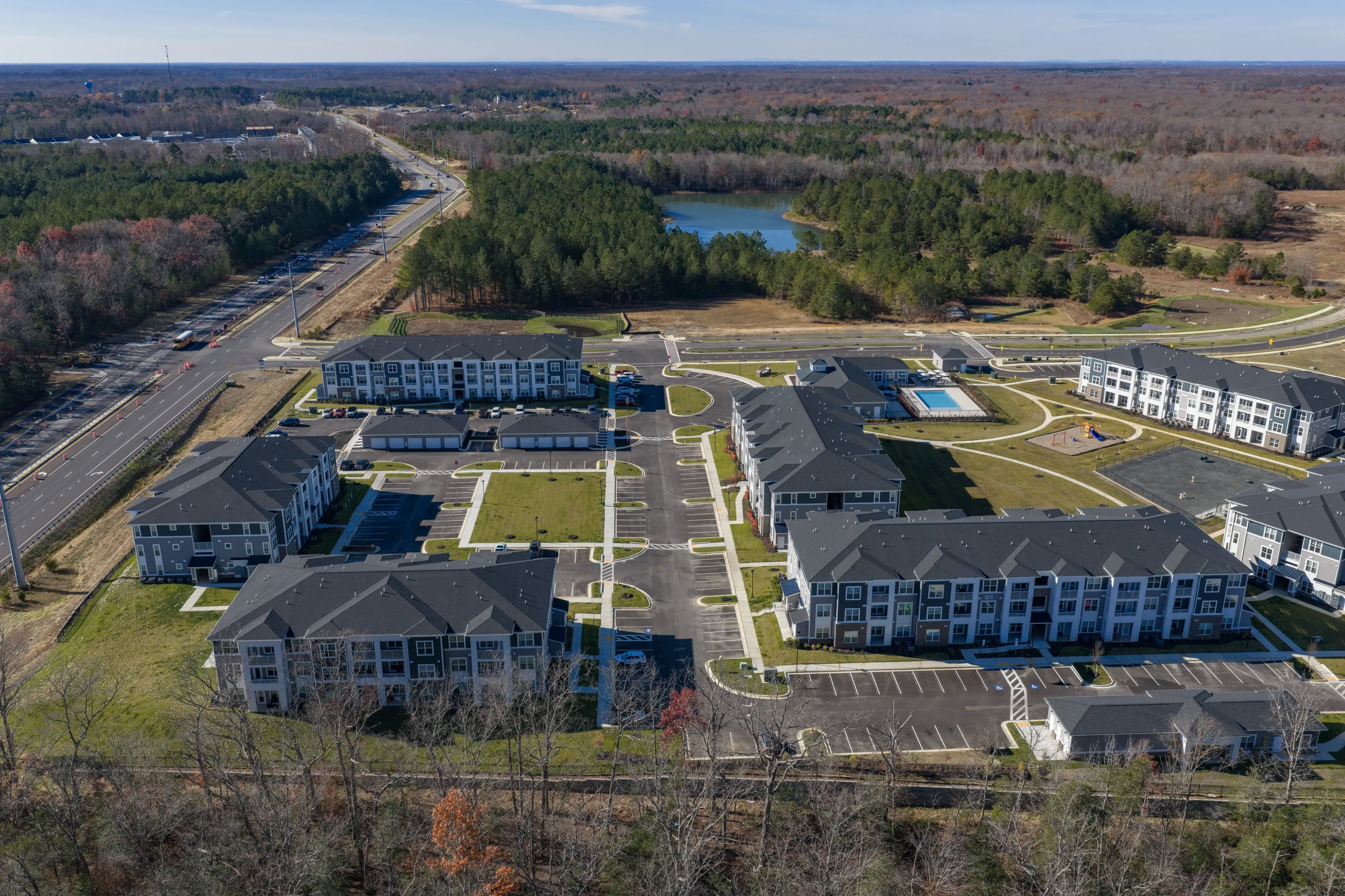 Aerial view of apartment buildings and amenities including a pool and playground.