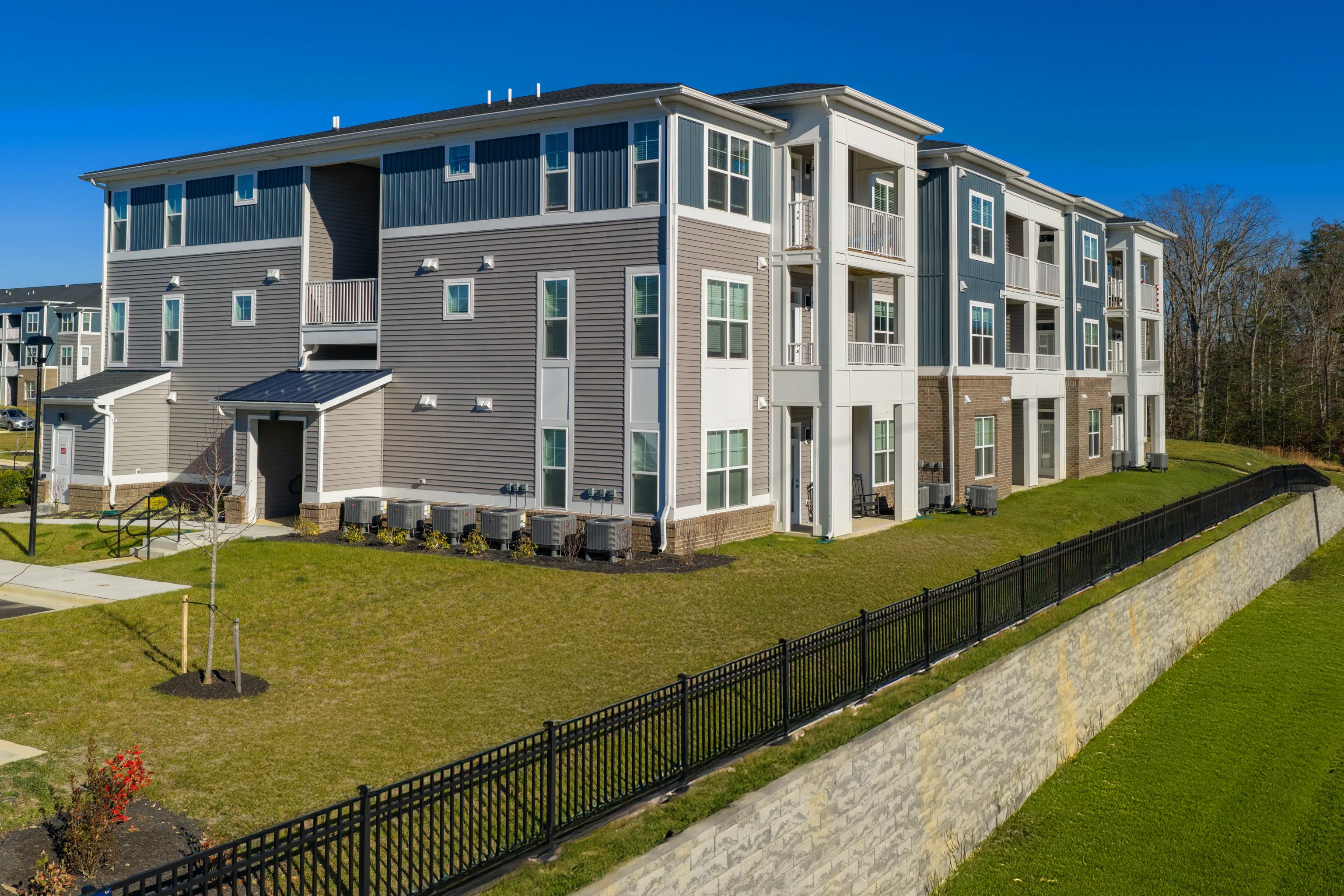 Exterior view of a modern apartment building with grey and blue siding.