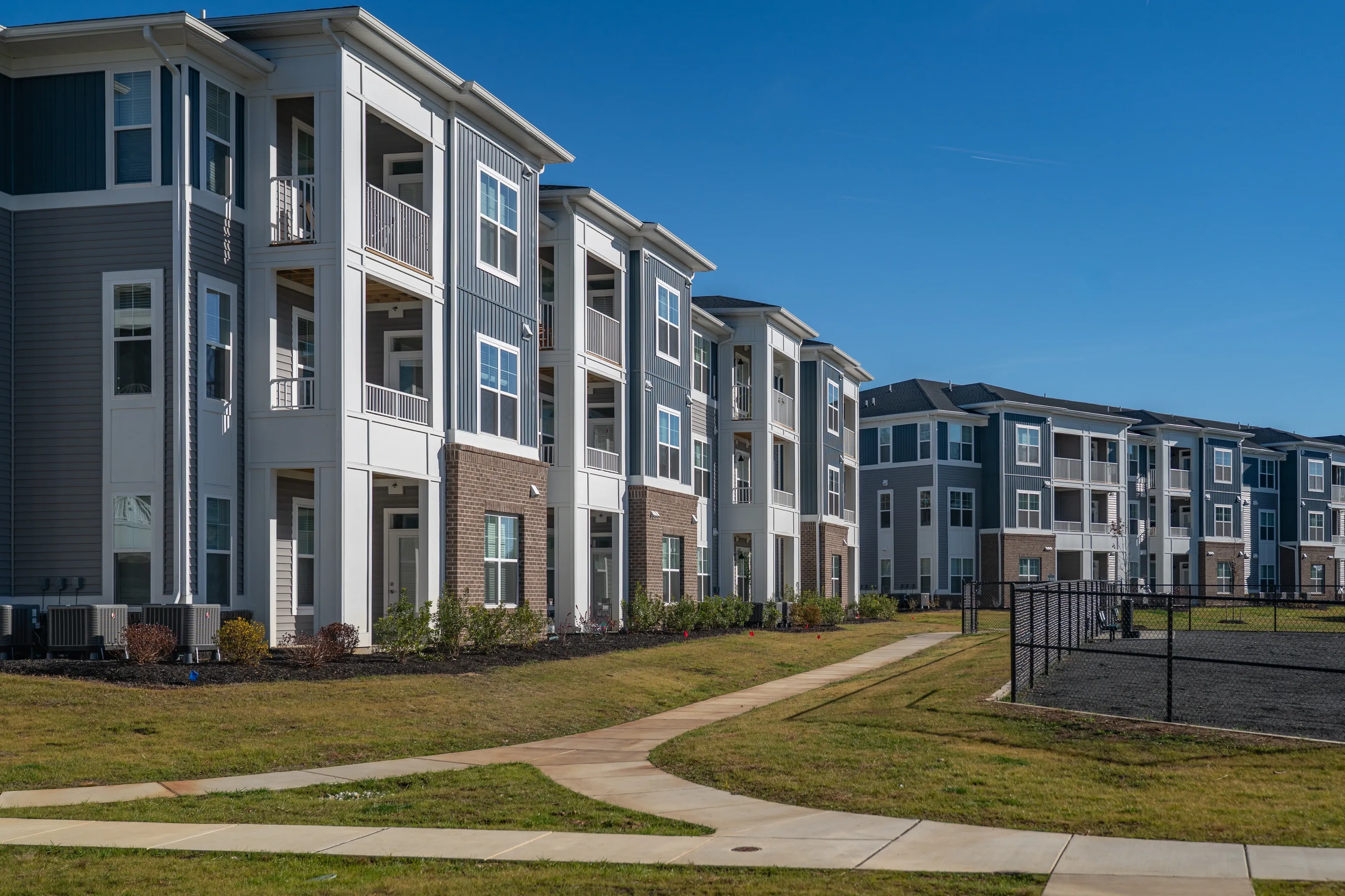 Exterior view of a multi-story apartment building with balconies and blue sky.