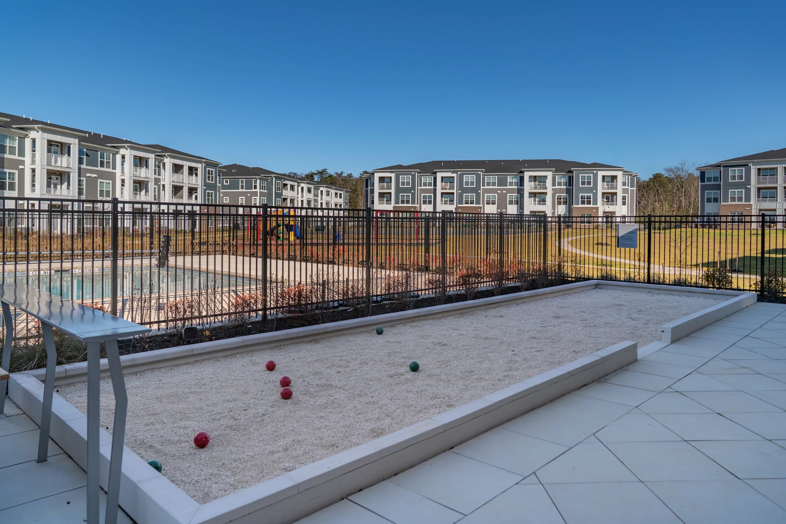 Bocce ball court and swimming pool with apartment buildings in the background.