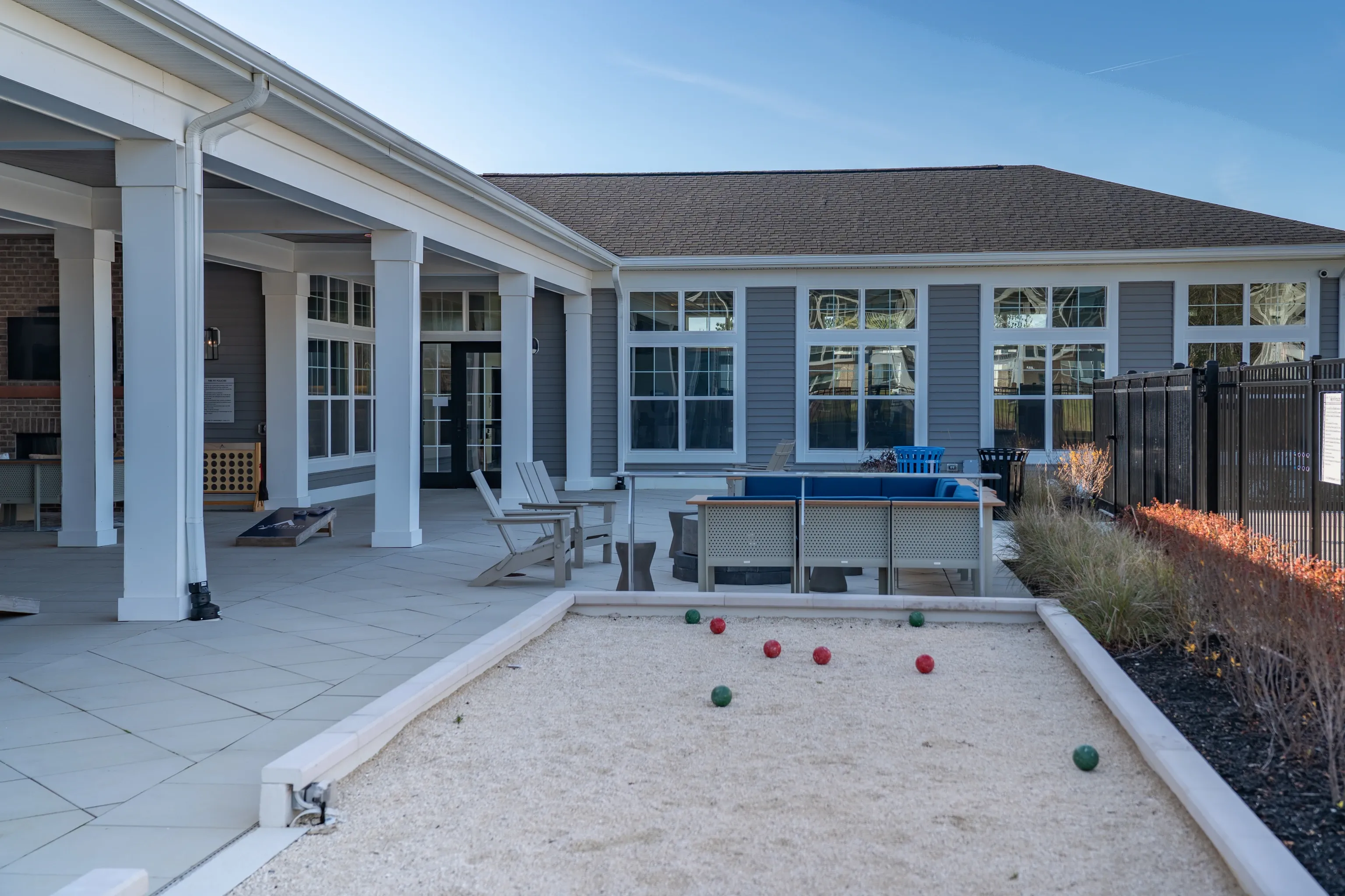 Outdoor patio with bocce ball court, seating area, and cornhole game.